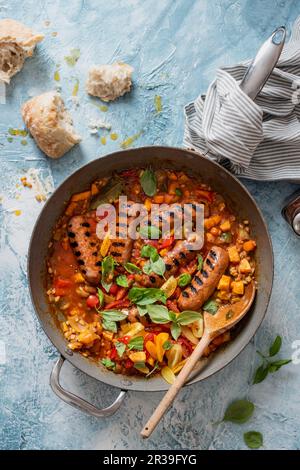 Ein Topf Chorizo-Würstchen mit Perlgerste, Süßkartoffeln, Tomaten und Basilikum Stockfoto