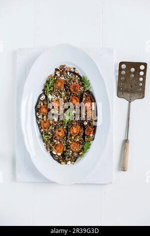 Dies ist ein gebackenes Aubergine-Gericht garniert mit einer Mischung aus Quinoa, frischen Kräutern und Fetakäse (glutenfrei) Stockfoto