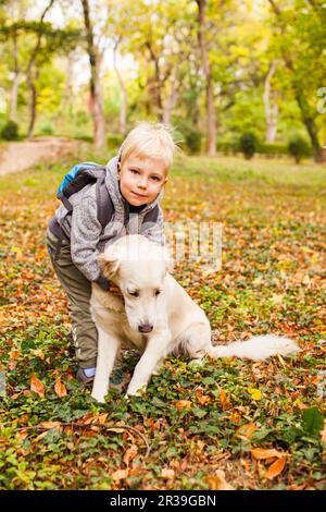 Kleiner Tierliebhaber auf einem Herbstspaziergang mit Haustierhund Stockfoto