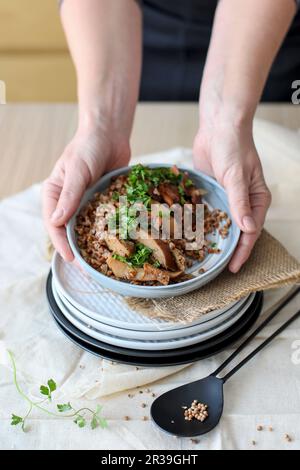 Pilze mit Buchweizen auf dem Teller in weiblichen Händen Stockfoto