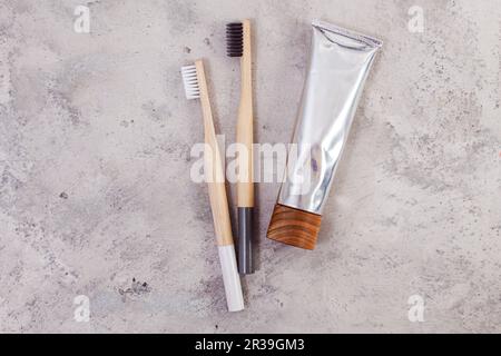 Bambuszahnbürsten und Zahnpasta auf minimalistischem Betonbackgroud. Null-Abfall-Konzept Stockfoto