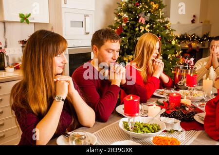 Erwachsene Brüder und Schwestern beten vor dem Weihnachtsessen Stockfoto