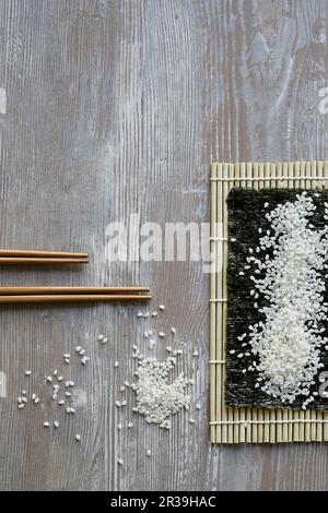 Sushi-Reis auf einem Nori-Blatt und einer Bambusmatte (Japan) Stockfoto