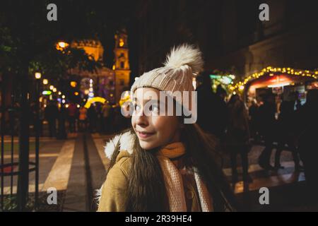 Schönes kleines Mädchen wünscht sich Neujahrsnacht auf dem Weihnachtsmarkt was Stockfoto