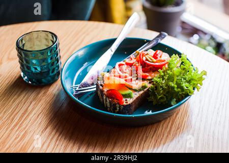 Gesundes Frühstück. Avocado-Toast mit Lachs auf blauer Keramikplatte Stockfoto