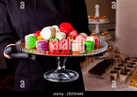 Bunte Makronen und andere Desserts werden auf dem Tisch serviert Stockfoto