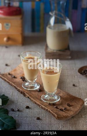 Cremiger Kaffeelikör in einer Karaffe und über Eis in Likörgläsern serviert Stockfoto