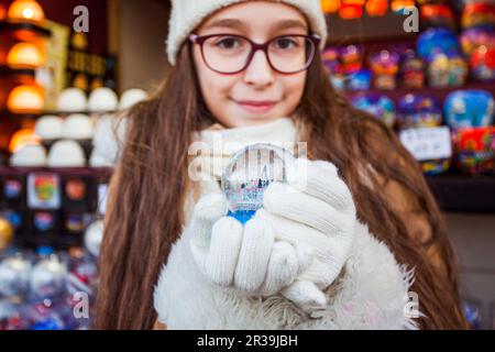 Glückliches Mädchen, das magische Souvenir auf dem weihnachtsmarkt hält Stockfoto