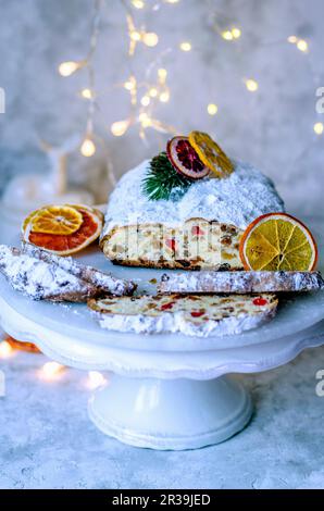 Weihnachtsstollen auf einem weißen Ständer, geschmückt mit trockenen Orangenscheiben und Girlande Stockfoto