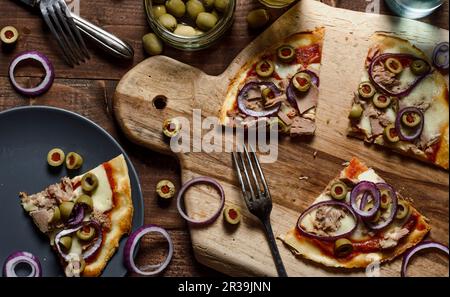 Pizza mit Thunfisch, roten Zwiebeln, grünen Oliven und Mozzarella Stockfoto