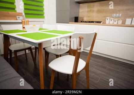 Modernes, weißes, modernes Küchen-Interieur. Stilvoller Esstisch und Stühle. Stockfoto