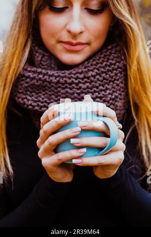 Mädchen, die im Herbst heißen Tee im Freien genießen. Damenhände mit perfekter Maniküre. Herbststimmung und Lifestyle. Stockfoto