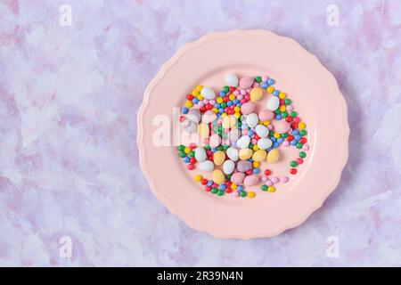 Teller mit Osterzucker-Schokoladeneiern und bunten Schokoladenchips Stockfoto