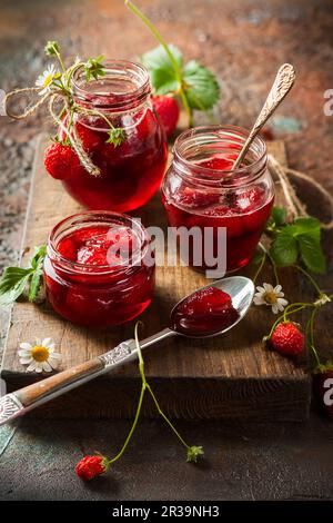 Hausgemachte Erdbeermarmelade in Glasgefäßen auf Holzbrett im rustikalen Stil. Gesundes Frühstück Stockfoto
