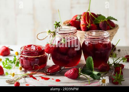 Hausgemachte Erdbeermarmelade in Glasgefäßen auf Holzbrett im rustikalen Stil. Gesundes Frühstück Stockfoto