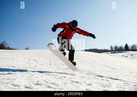 Männliche Snowboarder im Einsatz springen über Hügel Stockfoto