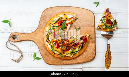 Köstliche Vorspeise im Sommer: Vegetarische Pizza mit gegrilltem Gemüse und Weichkäse auf Holzbrett. Draufsicht Stockfoto