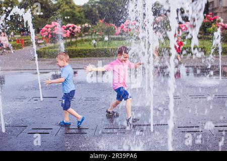 Zwei Kerle genießen kaltes Wasser in einem Brunnen Stockfoto