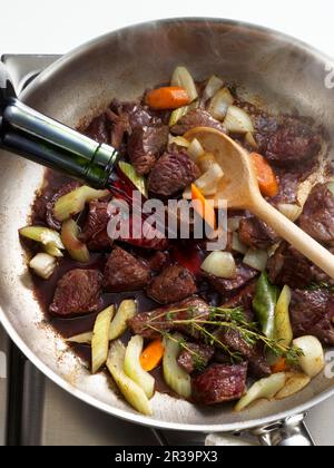 Ragout wird mit Rotwein entgast Stockfoto