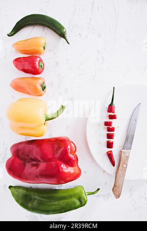 Verschiedene Paprika und Chilis werden in Scheiben geschnitten Stockfoto