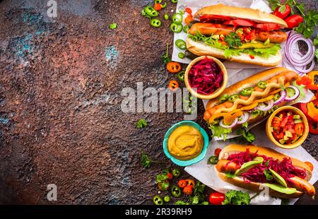Verschiedene köstliche Hot Dogs mit Gemüse und Saucen auf einem klassischen Serviertablett. Blick von oben. Stockfoto