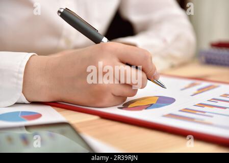 Eine Frau, die Einkommensdiagramme und -Diagramme analysiert. Geschäftsanalyse und Strategiekonzept. Stockfoto