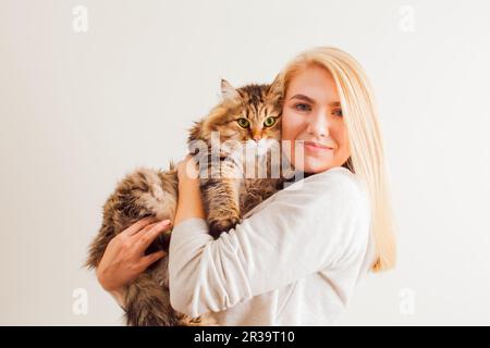 Eine schöne Frau, die eine neue adoptierte flauschige Katze mit grünen Augen hält Stockfoto