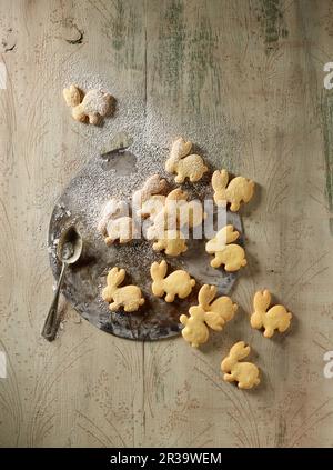 Kaninchen-förmige Kekse mit Puderzucker auf einem Backblech Stockfoto