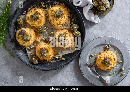 Ostereier mit Datteln überzogen, Kakao und Pistazien in Engelshaar-Nudelnestern Stockfoto