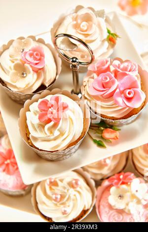 Festliche Cupcakes mit cremefarbenem Belag und Zuckerblumen Stockfoto