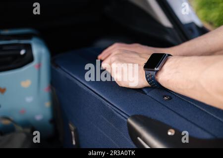 Nahaufnahme von menschlicher Hand. Nehmen Sie den Koffer aus dem Panzer. Reisekonzept Stockfoto