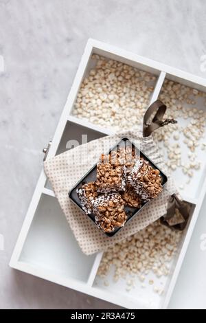 Buchweizen-Knäckebrot oder Puffweizen mit Schokolade auf einer traditionellen Holzbox Stockfoto