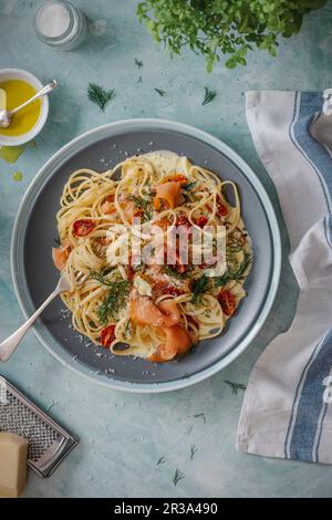 Pasta mit geräuchertem Lachs mit cremiger Dill- und Knoblauchsauce, gerösteten Kirschtomaten und Parmesankäse Stockfoto