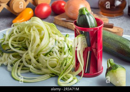 Zucchini-Nudeln mit spiralförmigem Gemüseschneider machen Stockfoto