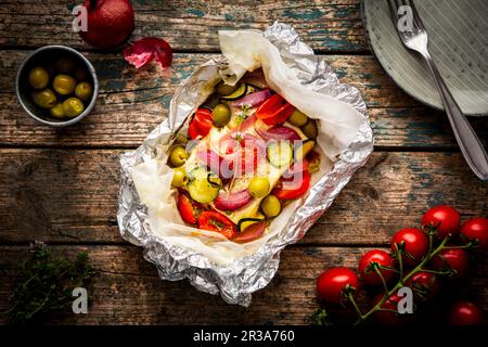 Feta mit Tomaten, Zucchini, Oliven, Zwiebeln und Thymian in Pergamentpapier Stockfoto