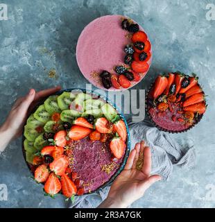 Vegane rohe Käsekuchen, Blick von oben mit Blaubeeren, Kirsche, Matcha-Tee, Orange, Cashew-Sahne, Kokosnussbutter und Kokosmilch und Mandelbasis, d Stockfoto