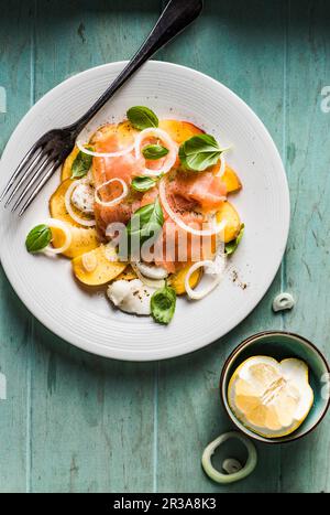 Caprese-Salat mit Nektarinen, Basilikum, Mozzarella-Käse und geräuchertem Lachs, gewürzt mit schwarzem Pfeffer, Salz und Olivenöl Stockfoto