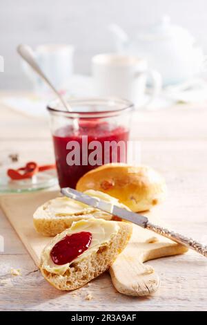 Saure Kirschmarmelade mit Himbeeren auf Brötchen mit Butter Stockfoto