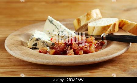 Süßer Birnen-Chutney mit Chili, serviert mit Blauschimmelkäse und Baguette in Scheiben auf einem Holzgericht Stockfoto
