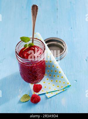 Ein Glas Mango und Himbeermarmelade mit frischem Zitronenbalsam Stockfoto