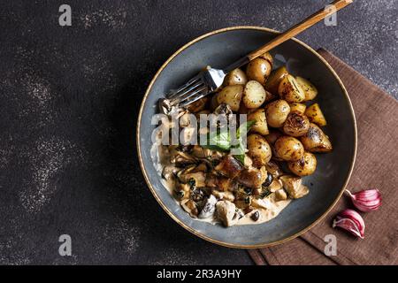 Weiße Pilze in Knoblauchcreme-Sauce mit gebratenen jungen Kartoffeln Stockfoto