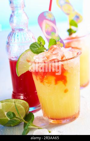 Sommerlicher Cocktail mit Pfirsichlikör, Orangensaft, Limette und Erdbeersirup Stockfoto