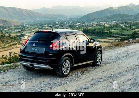 Nissan Juke parkte auf einer Schotterstraße mit einer wunderschönen Landschaft und Bergkulisse Stockfoto