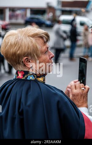 Sandnes, Norwegen, Mai 17 2023, Seniorin trägt traditionelles norwegisches Kleid mit einem Mobiltelefon Stockfoto