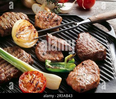 Verschiedene Fleisch- und Gemüsesorten auf einem Grill Stockfoto