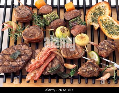 Verschiedene Wildfleisch- und Gemüsesorten auf einem Grillregal Stockfoto