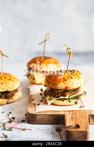 Hausgemachte Mini-Burger mit Bambusbrochetten. Sandwiches mit Fleischpasteten, Käse, Gurken und Schoko Stockfoto