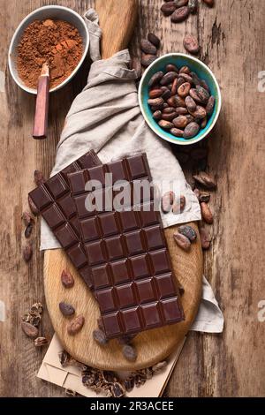 Schokoriegel, Kakaopulver und Kakaobohnen auf Holzbrett Stockfoto