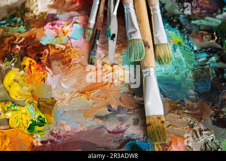 Kunstpinsel und Ölfarben auf Holzpalette. Makrokünstlerpalette, Texturen gemischte Ölfarben i Stockfoto