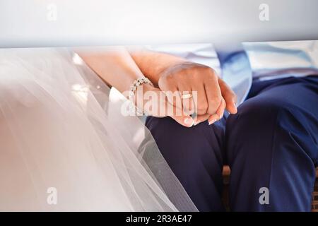 Die Hände der Braut und des Bräutigams in den Eheringen unter dem Tabelle Stockfoto